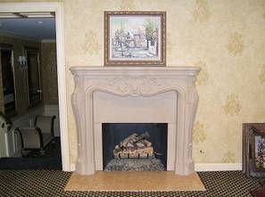 Fireplace with a painting above it, set against patterned wallpaper.