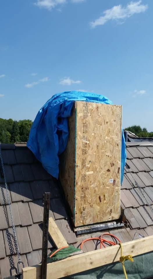 Chimney repair: OSB box on rooftop, covered with blue tarp, scaffolding visible.