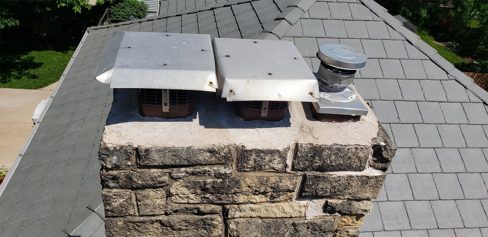 Chimney with three flue covers and a gray roof.
