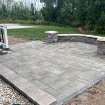 A patio with a bench and a fire pit in the middle of a yard.