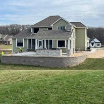 A large house is sitting on top of a lush green field.
