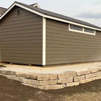 A small shed is sitting on top of a stone wall.