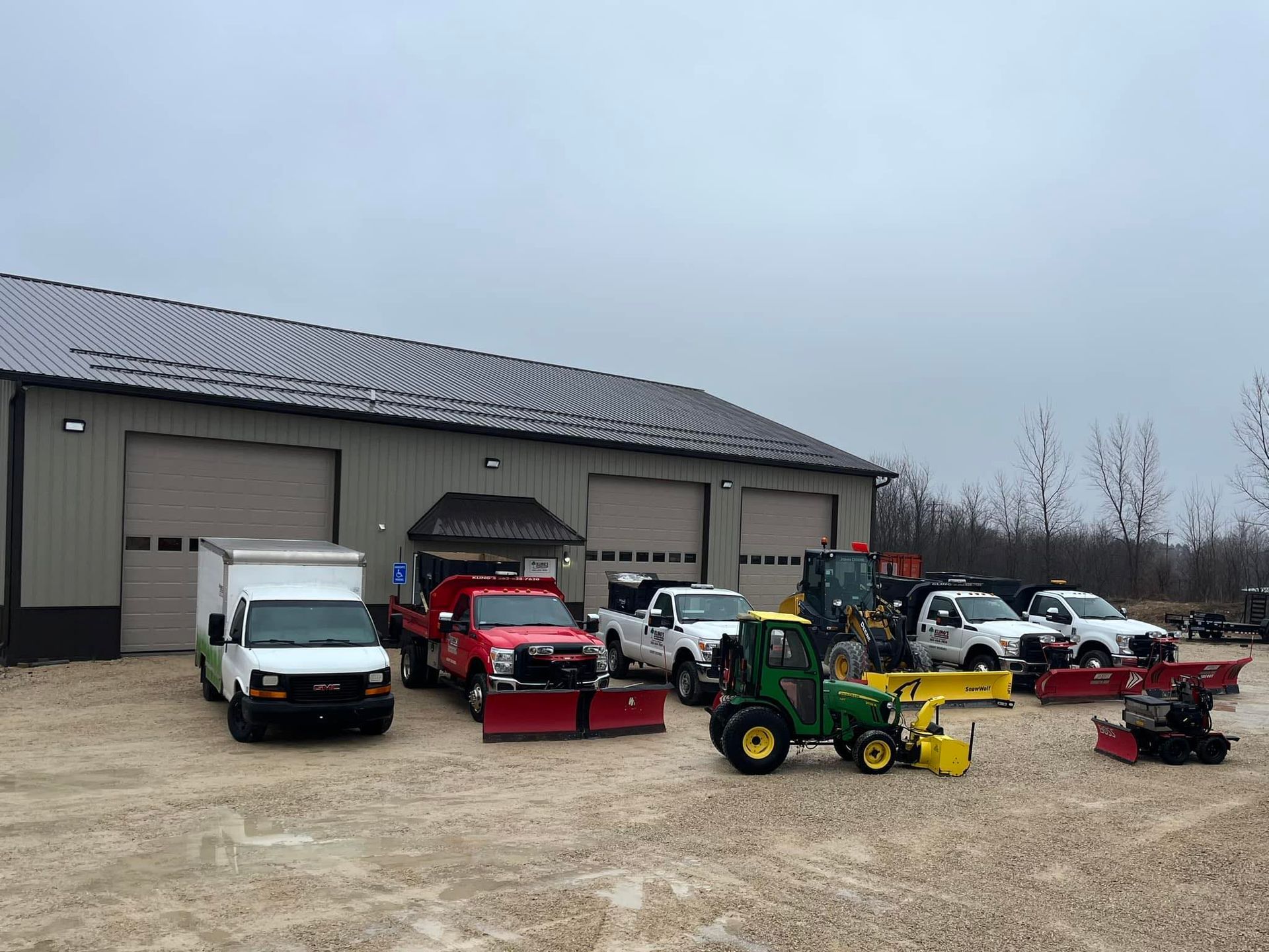 A row of snow plows are parked in front of a building.