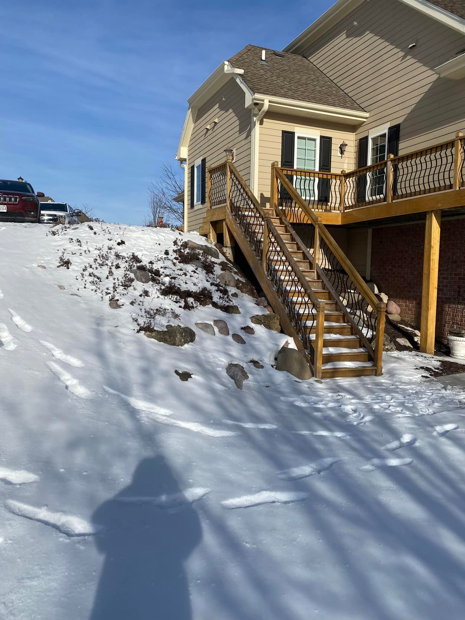 A house with a deck and stairs in the snow.