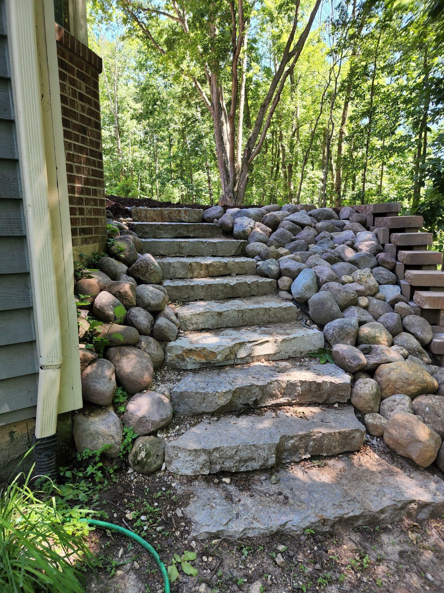 A set of stone stairs leading up to a house surrounded by rocks.