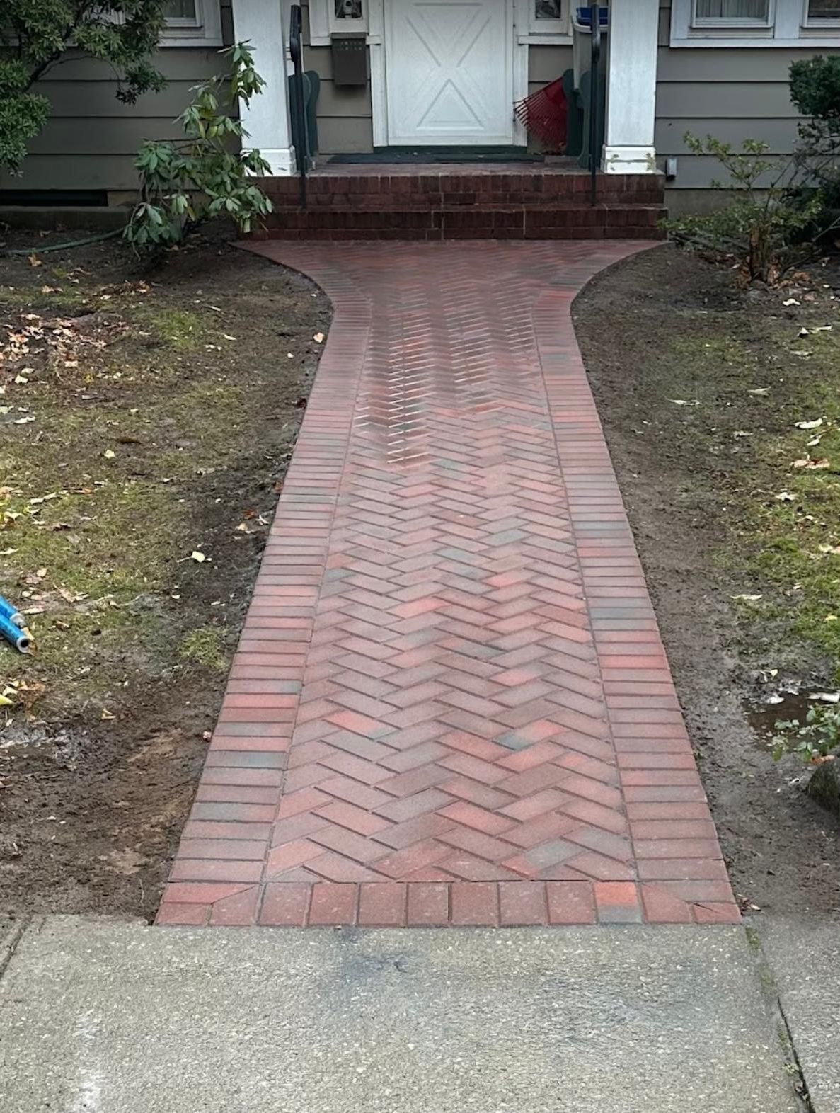 A brick walkway leading to the front door of a house