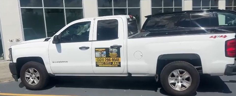 A white truck is parked in a parking lot in front of a building.