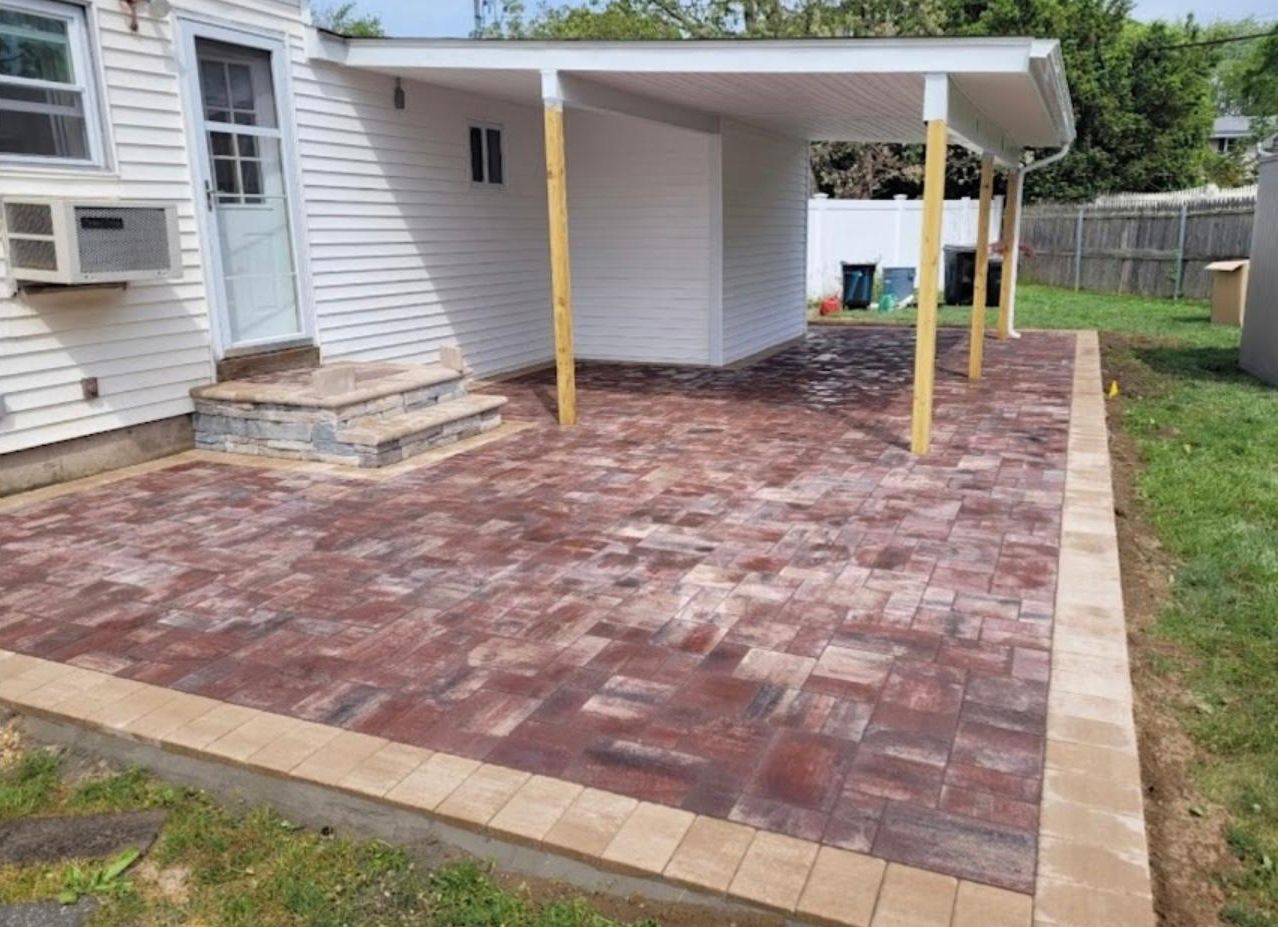 A brick patio is being built in front of a house.
