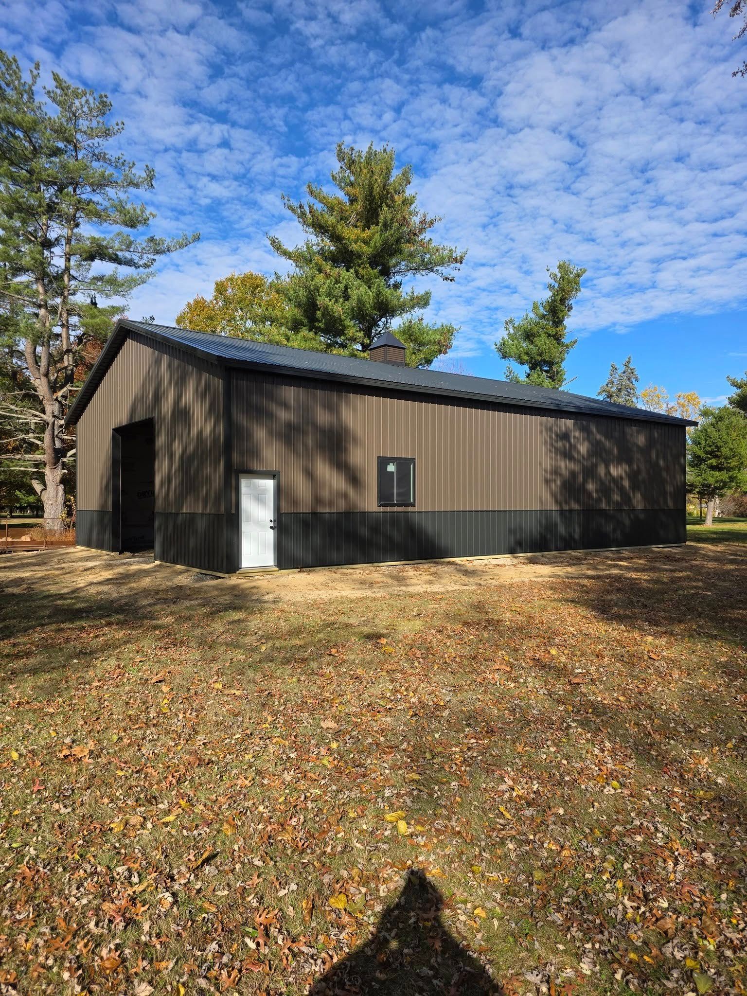 Brown and black metal barn with a blue sky background.