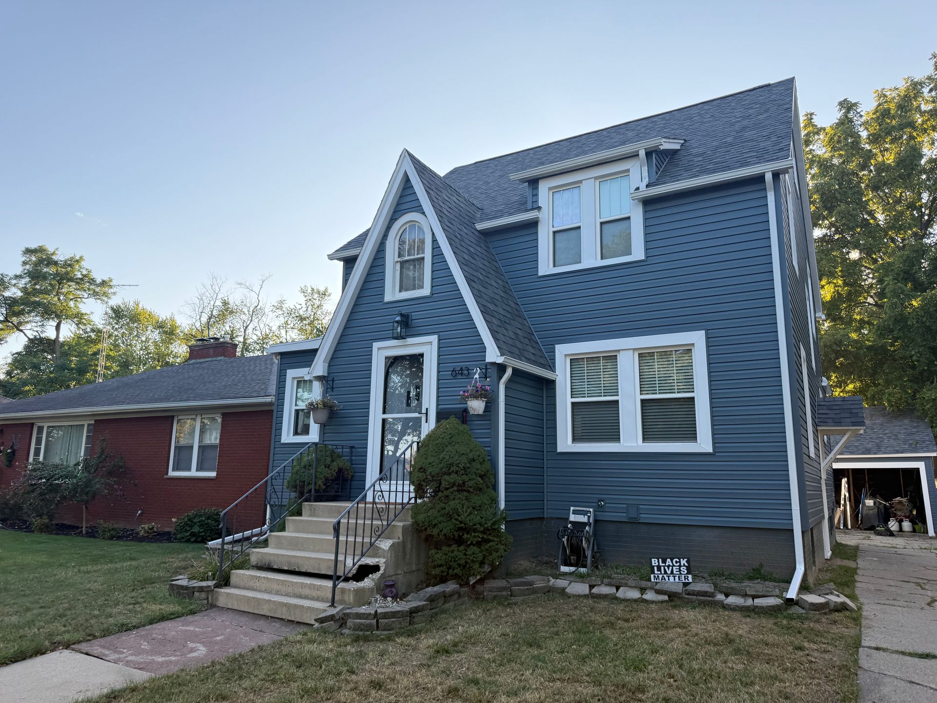 Blue house with white trim, steps leading to front door. Red house next door.