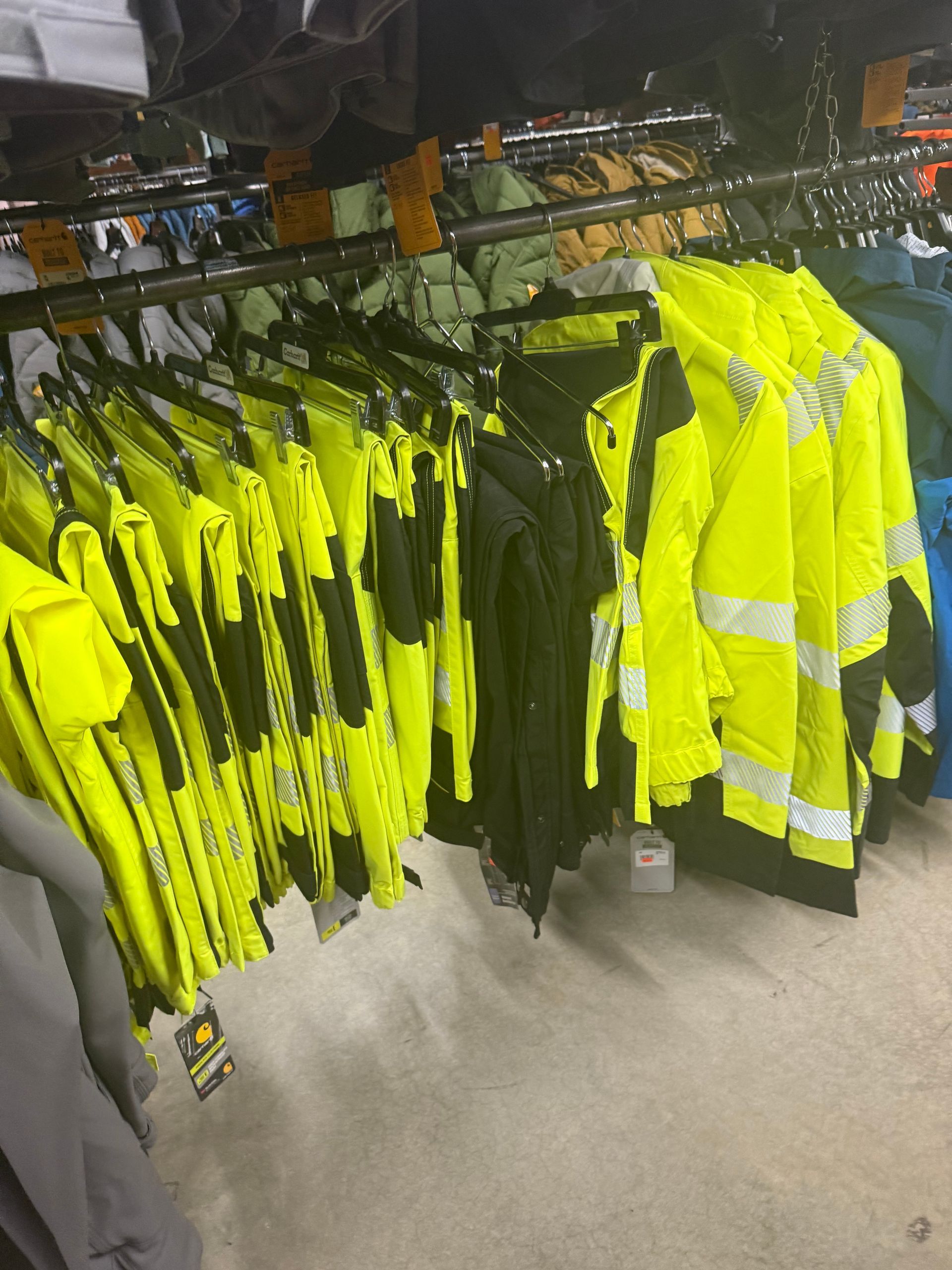 A bunch of yellow jackets are hanging on a rack