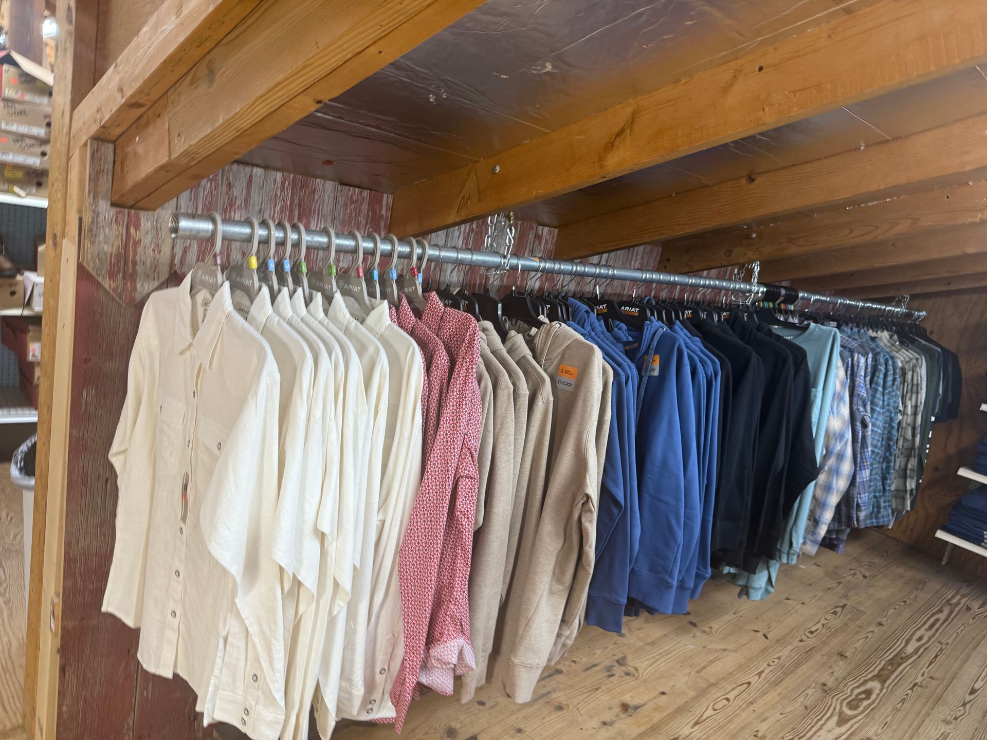 A row of shirts are hanging on a rack in a closet
