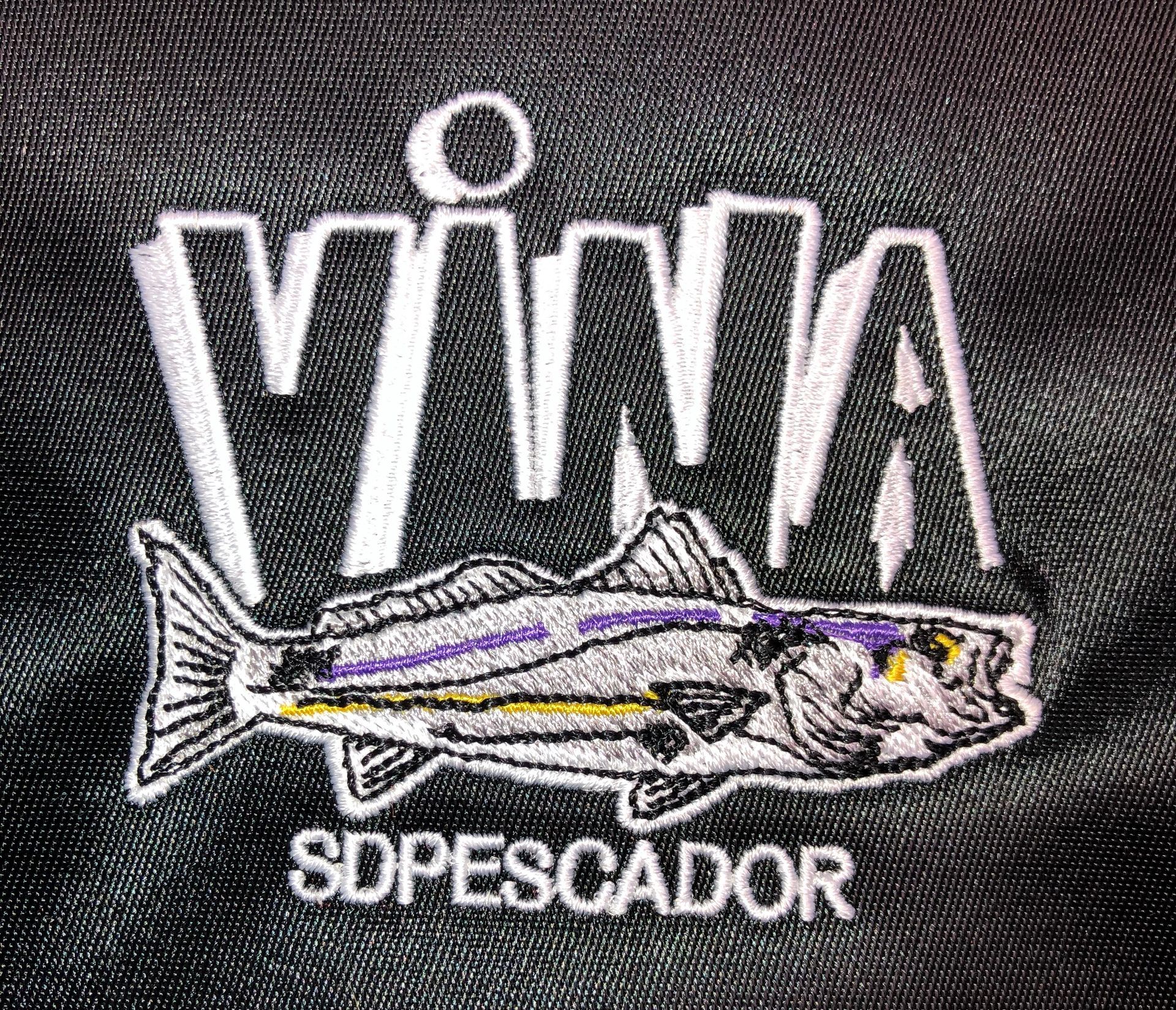 A close up of a embroidered logo with a fish on a black shirt.