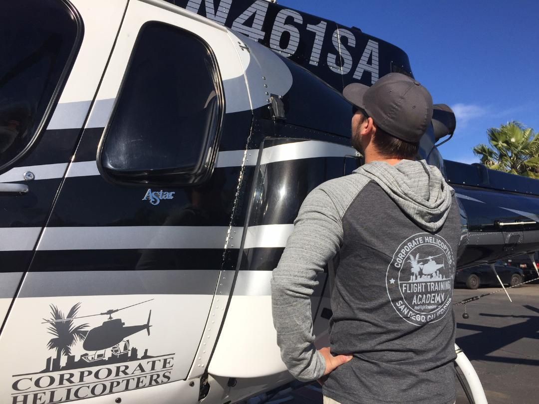 A man standing in front of a corporate helicopter