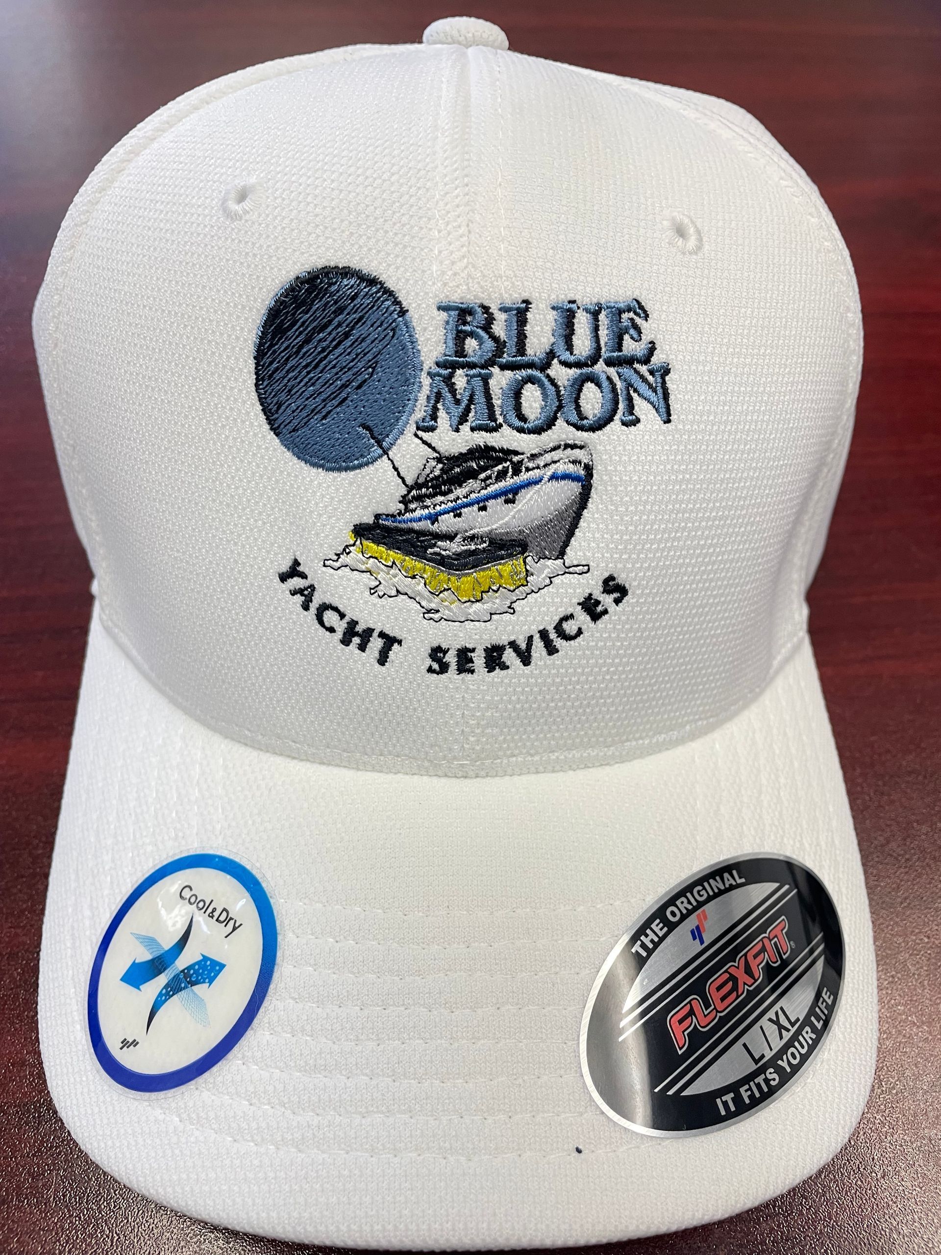 A white baseball cap with blue moon yacht services embroidered on it