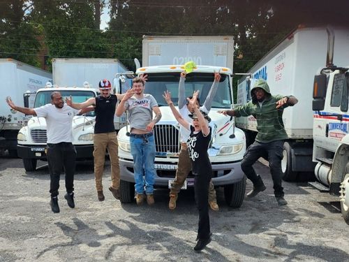 A group of people jumping in front of trucks, celebrating.