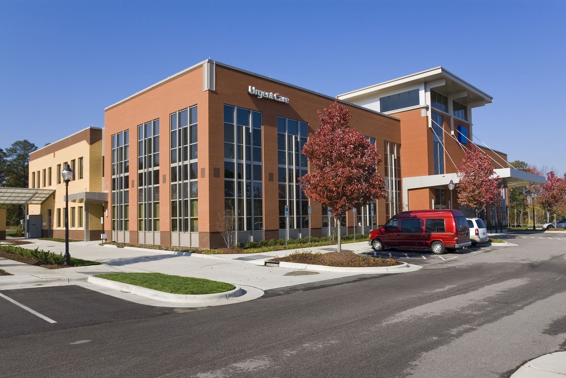 A red van is parked in front of a large building