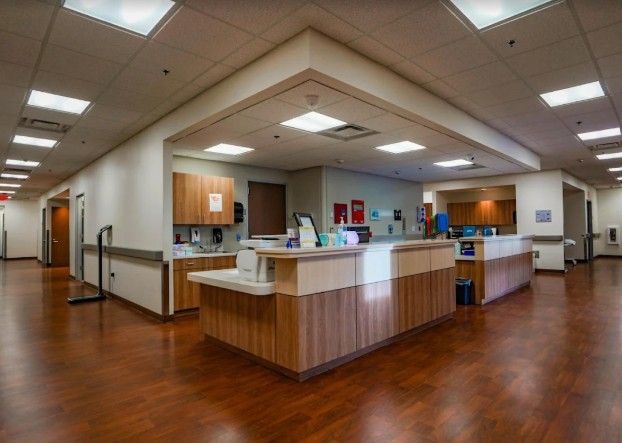 A nurse 's station in a hospital with wooden floors and cabinets.