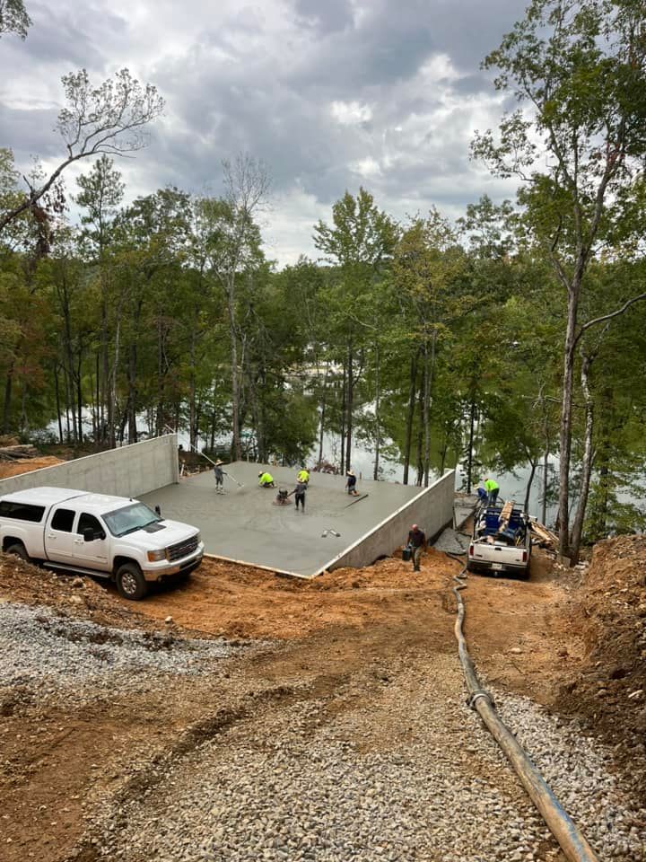 A white truck is parked on top of a dirt hill next to a lake.