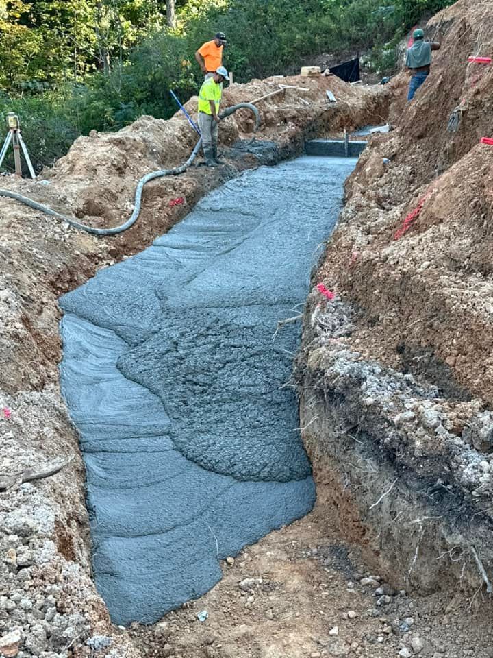 A large pile of concrete is being poured into a hole in the ground.
