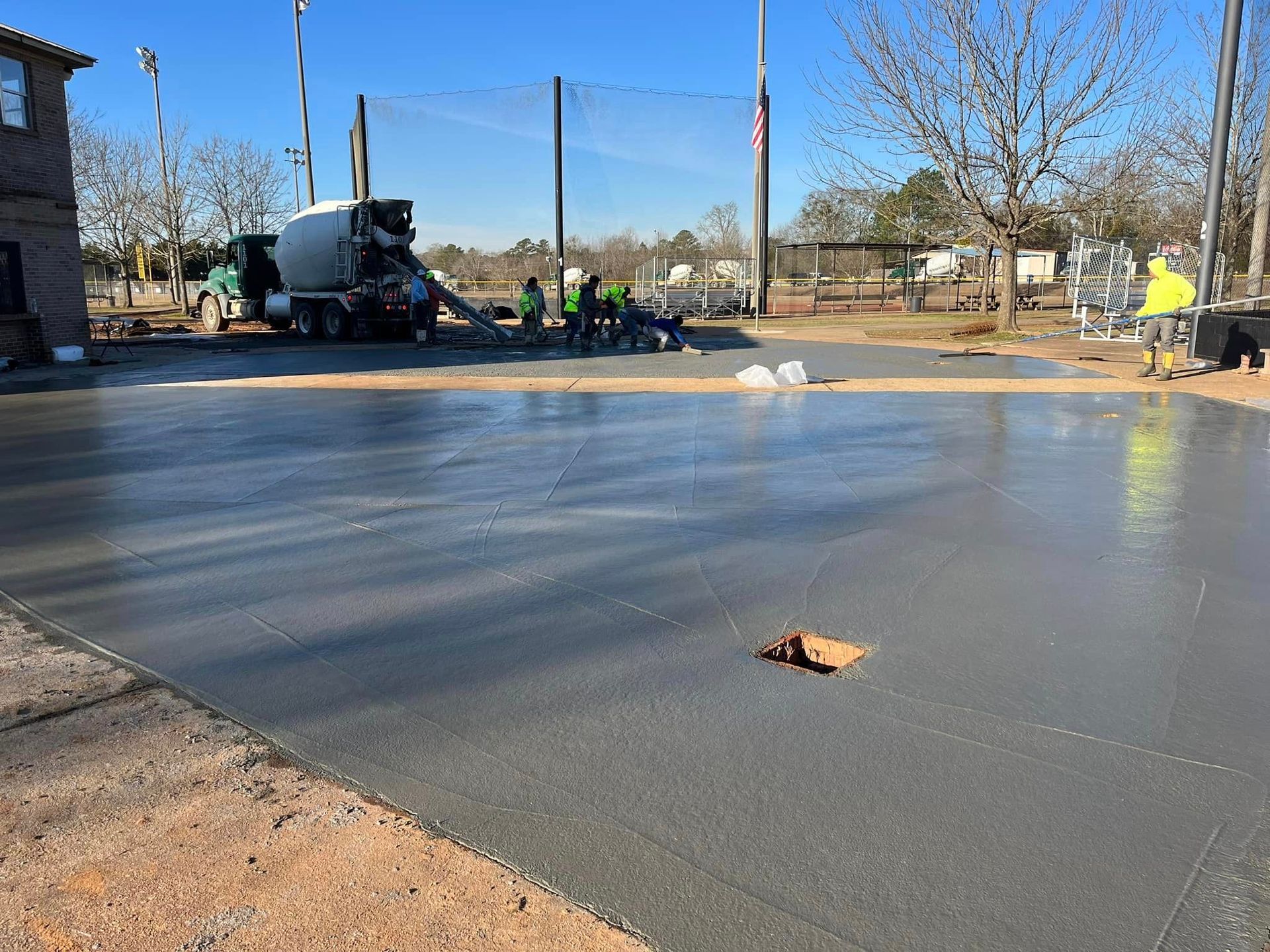 A cement truck is pouring concrete into a driveway.