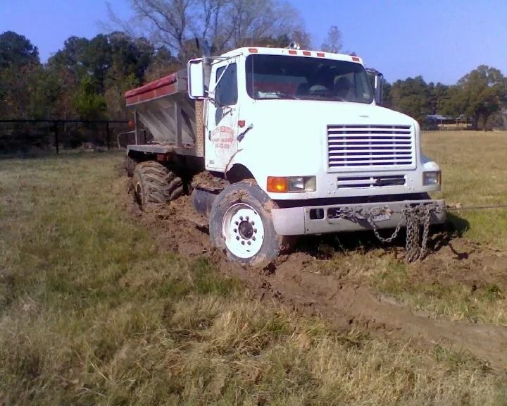 White dump truck driving through grassy field