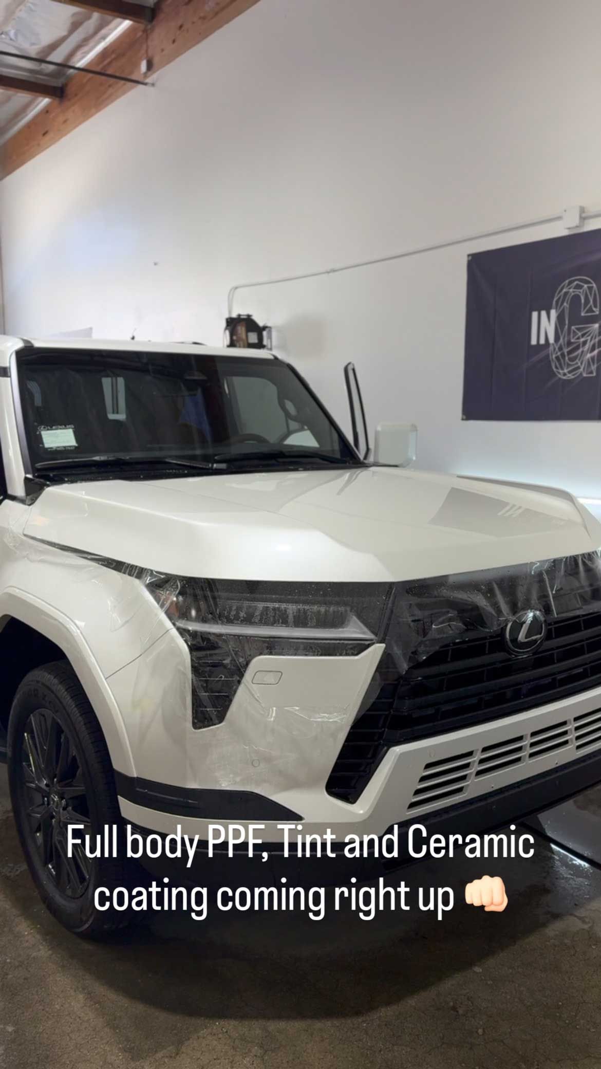 White SUV in a shop, covered in protective film. Text reads, 