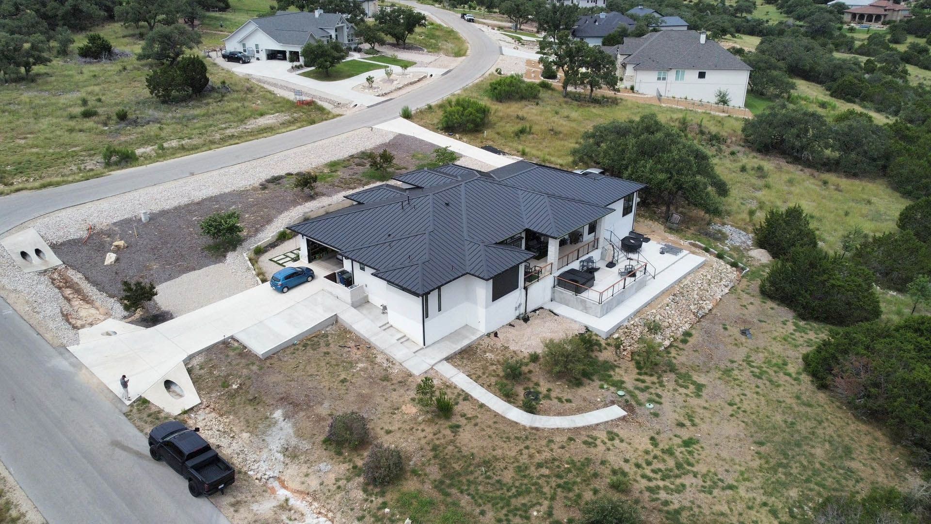 Aerial view of a modern white house with a dark roof on a hillside