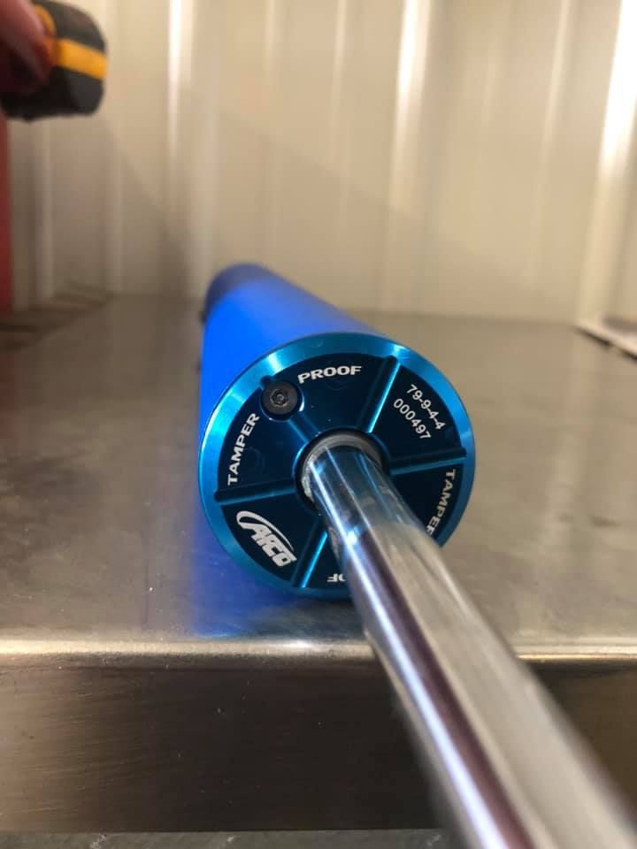 Close-up of a blue shock absorber. Details on the end cap include the word 