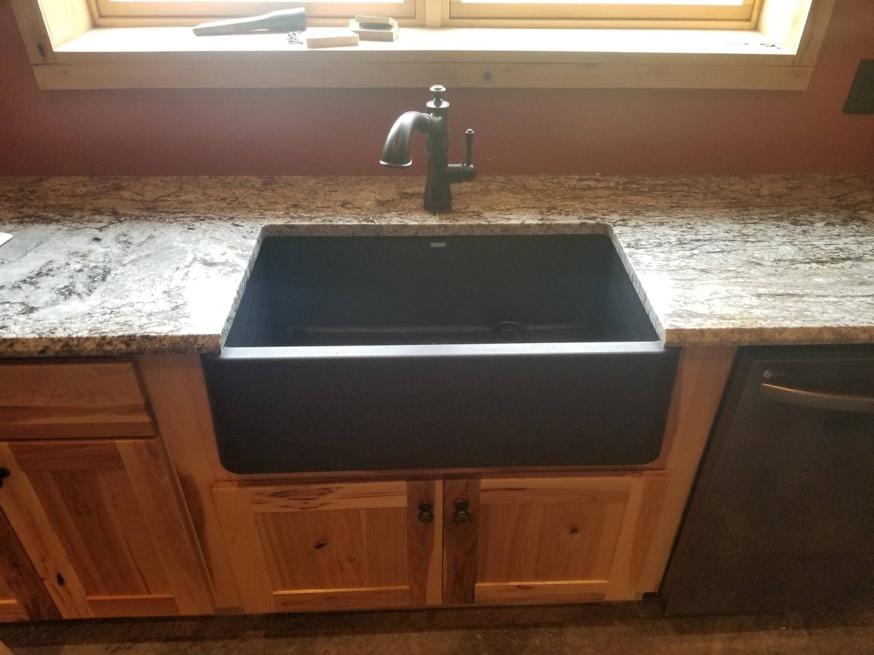 A kitchen sink with a faucet on top of a granite counter top.