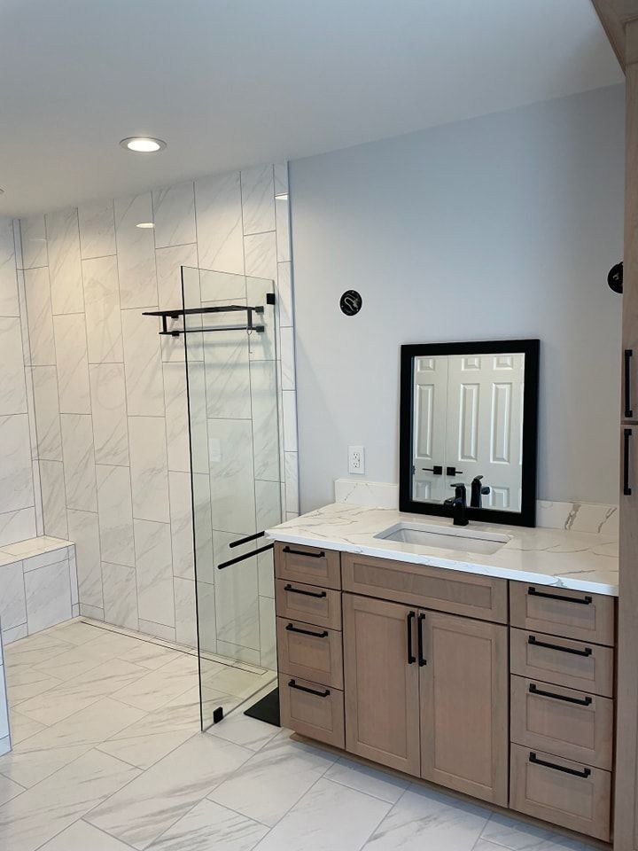 A bathroom with a sink , mirror and walk in shower.