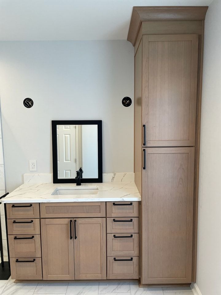 A bathroom with a sink , mirror and cabinets