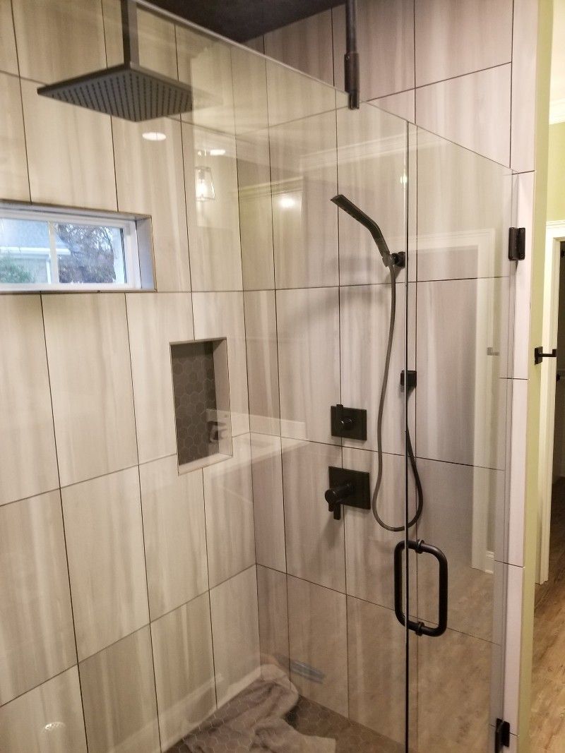 A bathroom with a walk in shower with a glass door and a shower head.