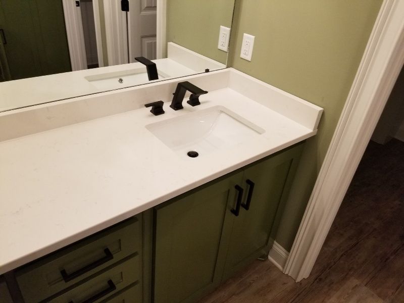 A bathroom with a sink , mirror and green cabinets