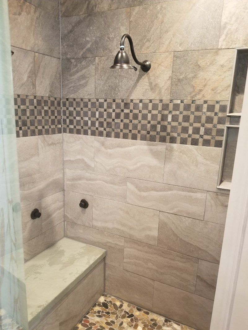 There is a shower with a bench and a shower head.