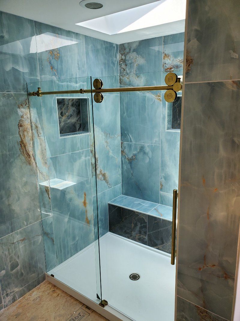 A bathroom with blue tiles and a sliding glass shower door.