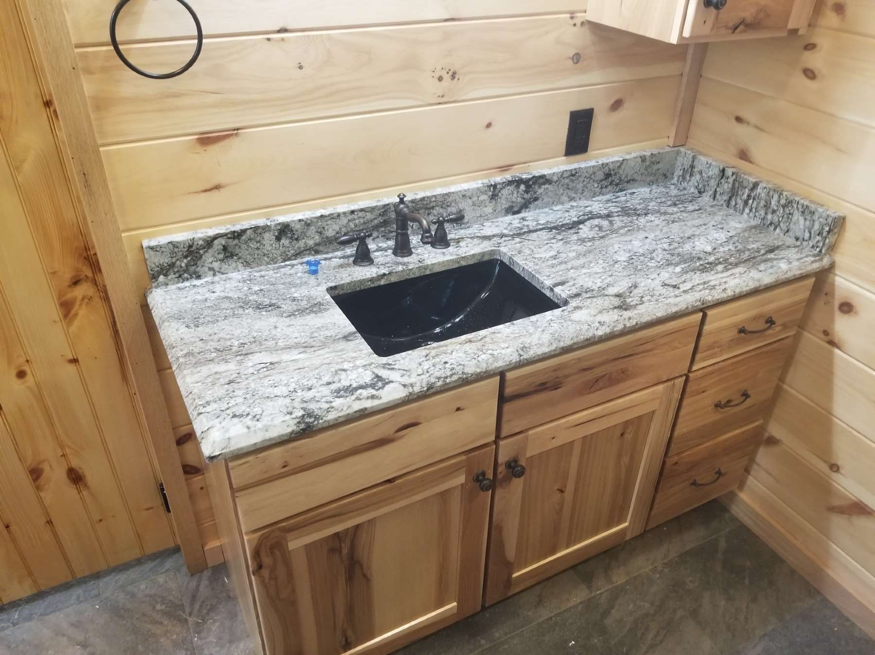 A bathroom sink with a granite counter top and wooden cabinets.