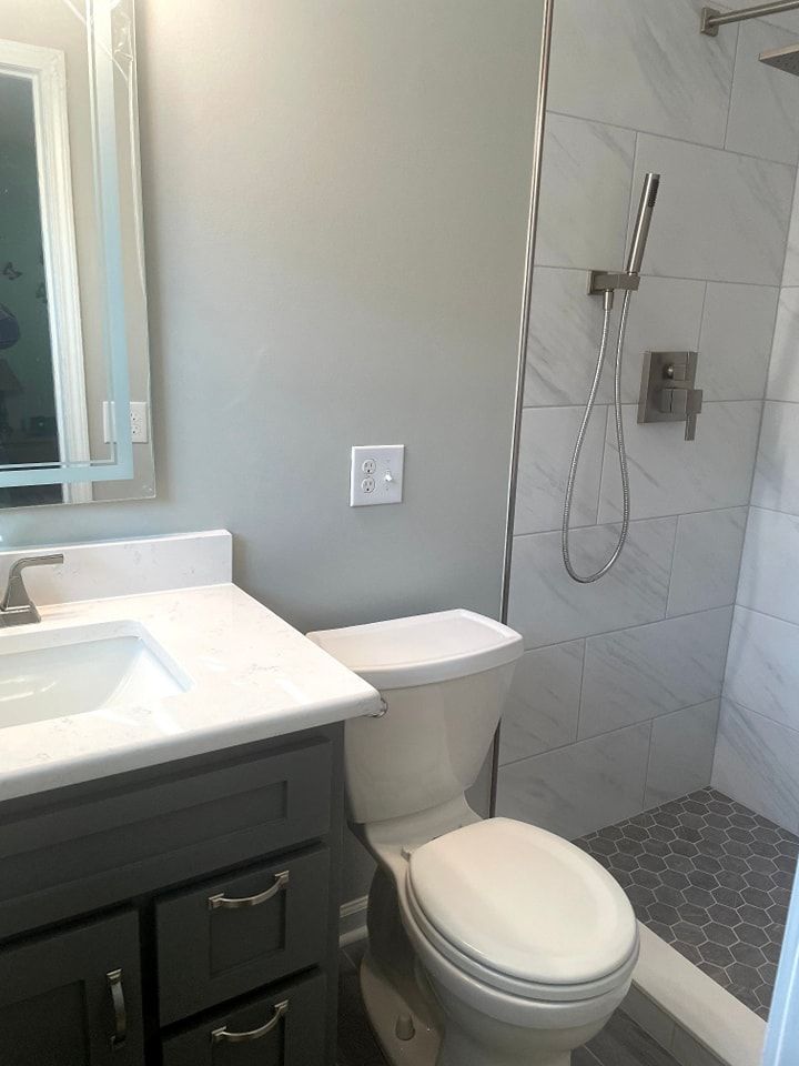 A bathroom with a toilet , sink and shower.
