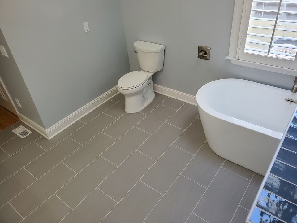 A bathroom with a toilet , tub and window.