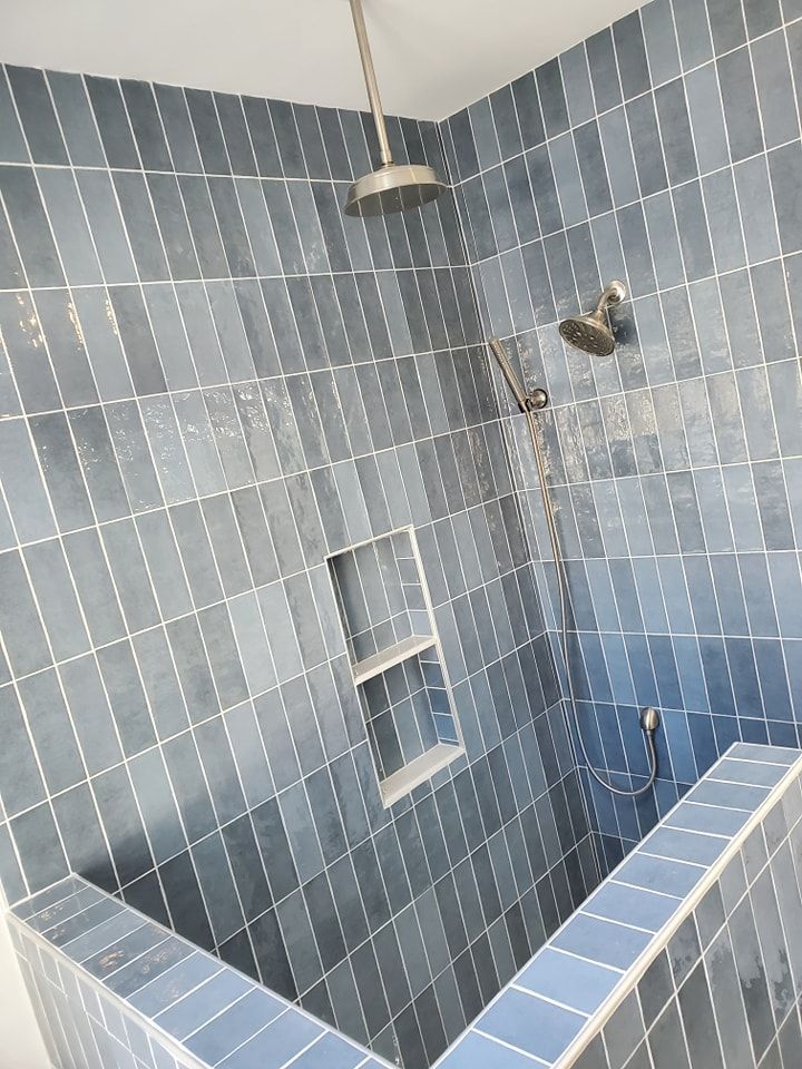A shower with blue tiles and a shower head.