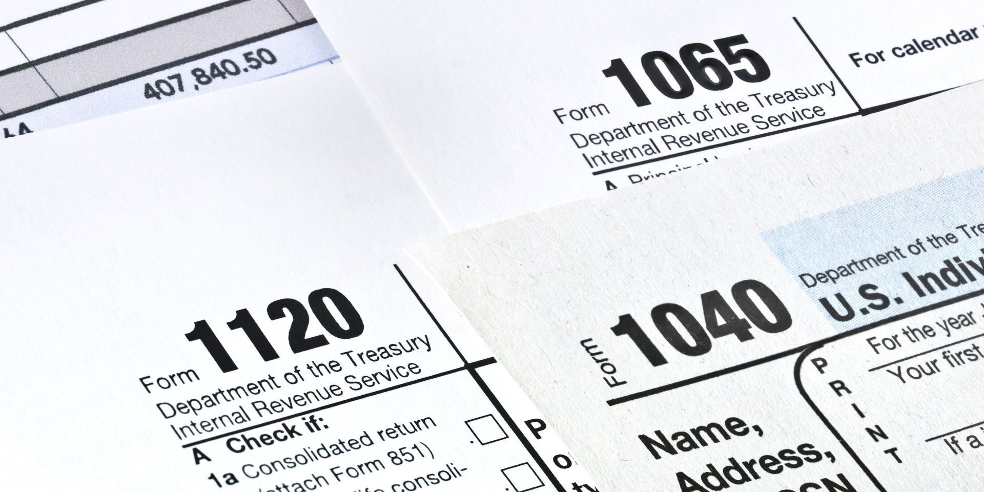 Tax forms: 1040, 1120, and 1065. Close-up view of IRS forms on white paper.