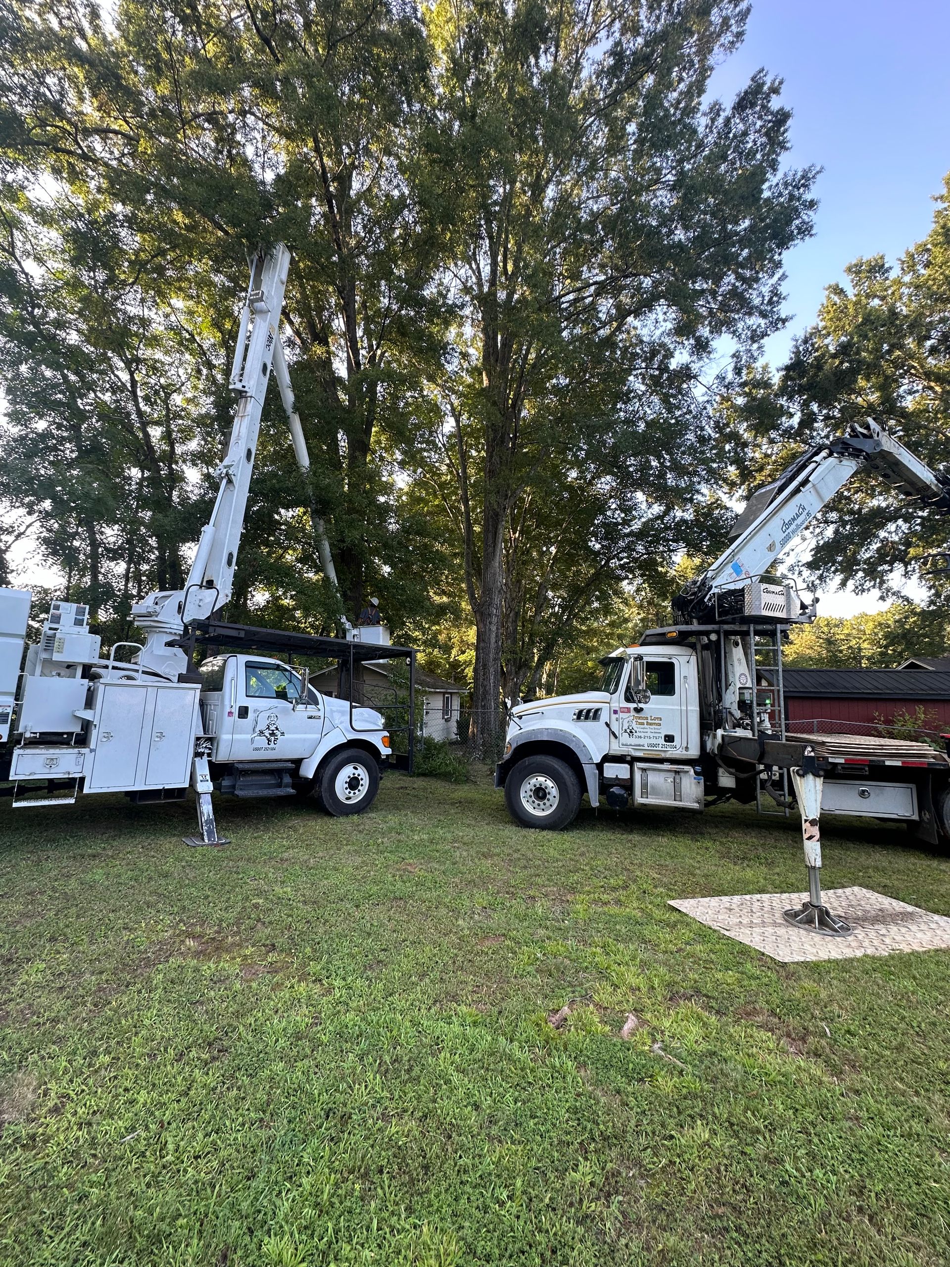 Two utility trucks are parked next to each other in a grassy field.
