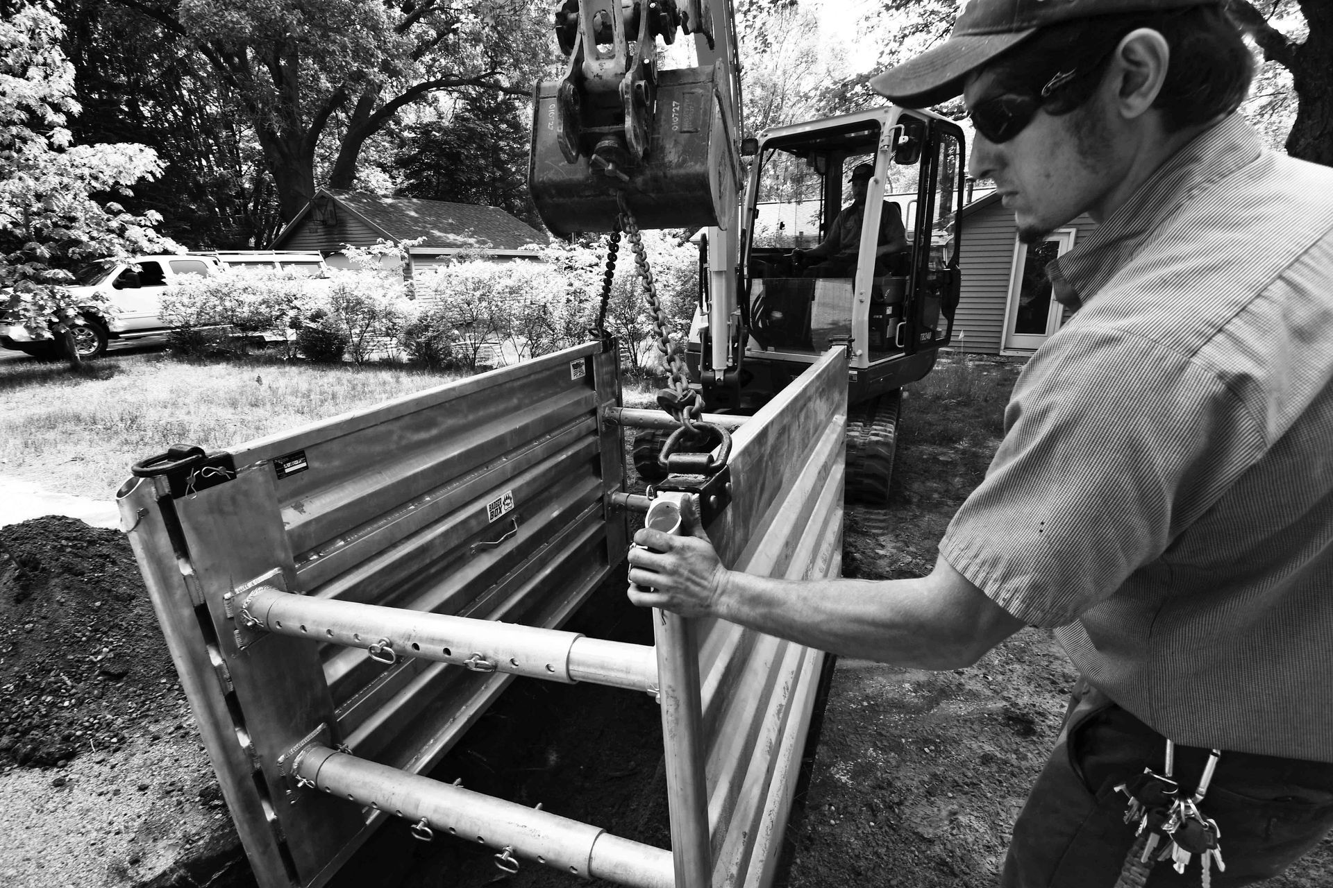Man working in a trench, using machinery. Black and white photo, outdoors, construction.