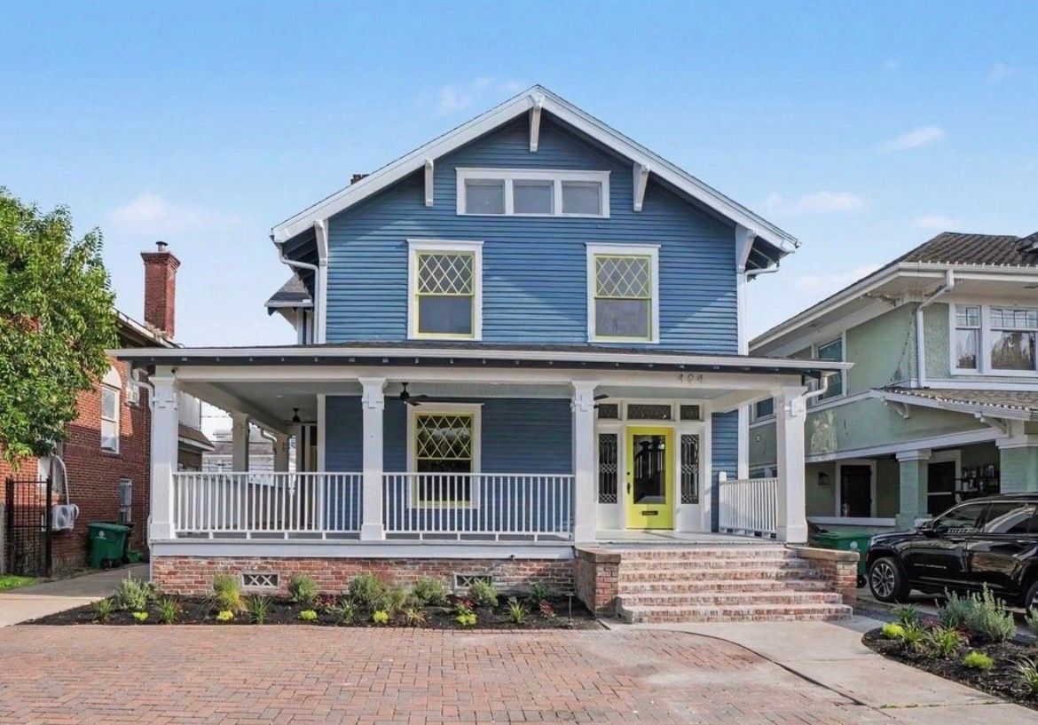 Blue two-story house with white trim and a front porch, viewed from the street