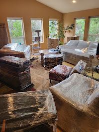 A living room filled with furniture wrapped in plastic.