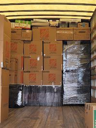 The inside of a moving truck filled with lots of cardboard boxes.