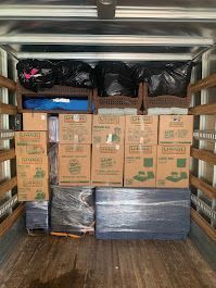 The back of a moving truck filled with boxes and bags.