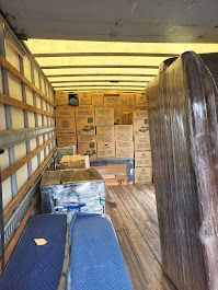 The inside of a moving truck filled with boxes and a mattress.