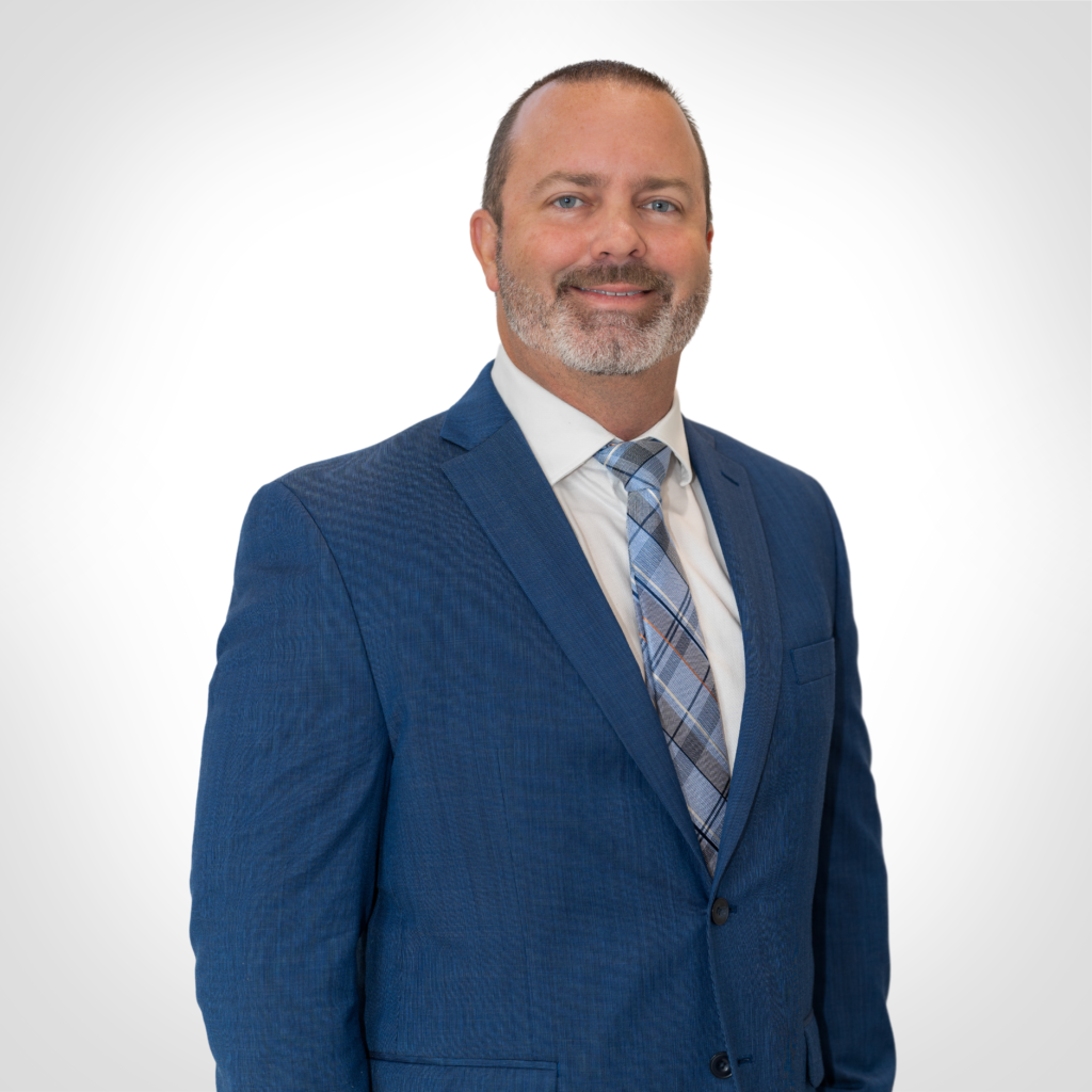 Man in a blue suit and plaid tie standing against a white background