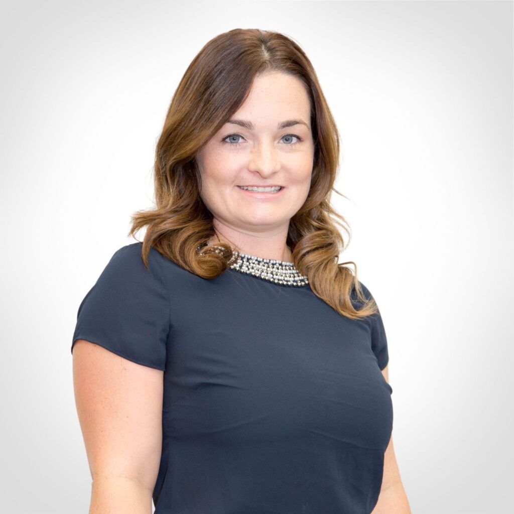 Woman in a dark blue top smiling against a white background
